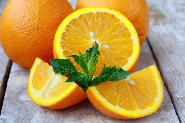 Cut into slices and whole oranges with mint leaf — Stock Photo, Image