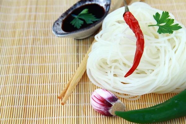 Fideos de vidrio asiáticos, chile y salsa de soja en estera de bambú — Foto de Stock