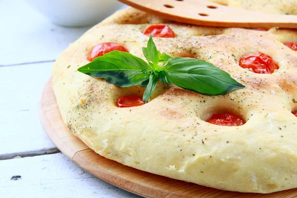 Italian Focaccia bread with tomatoes and basil on a cutting board — Stock Photo, Image