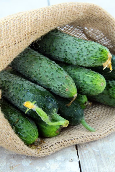 Cucumbers in a linen bag on a wooden table — Stock Photo, Image