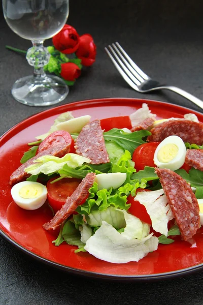 Ensalada con huevos de codorniz y salami en un plato rojo —  Fotos de Stock