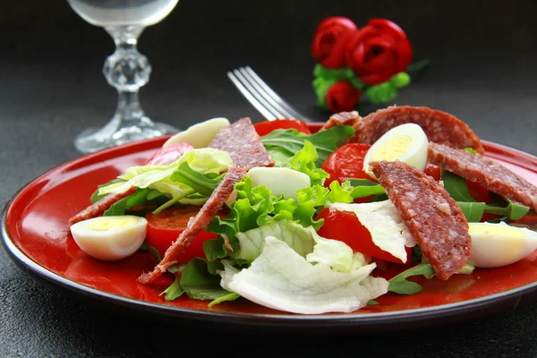 Sallad med vaktelägg och salami på en röd skylt — Stockfoto