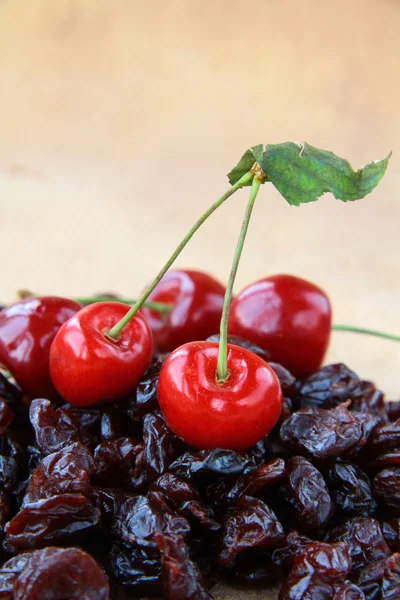 stock image Dried cherry and fresh cherries on a brown background