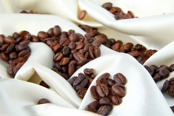 Coffee beans on a beige silk concept luxurious coffee — Stock Photo, Image