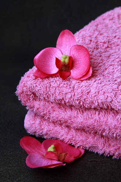 Pink towel and pink orchids on a black background — Stock Photo, Image
