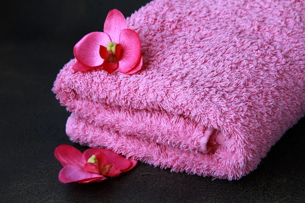 Różowy ręcznik i różowy storczyki na czarnym tle — Zdjęcie stockowe