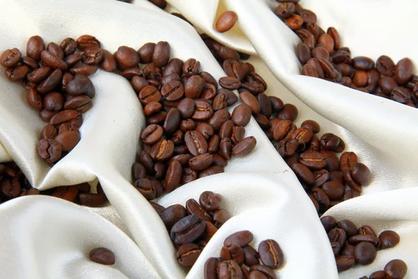 Grãos de café em um conceito de seda bege café luxuoso — Fotografia de Stock