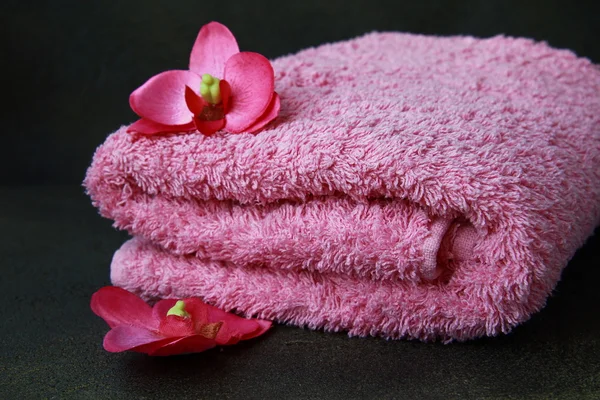 Roze handdoek en roze orchideeën op een zwarte achtergrond — Stockfoto