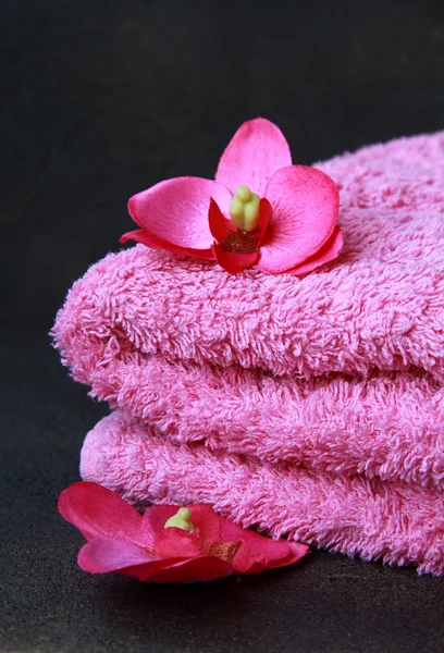 Różowy ręcznik i różowy storczyki na czarnym tle — Zdjęcie stockowe