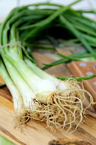 Young green organic onions on a wooden board — Stock Photo, Image