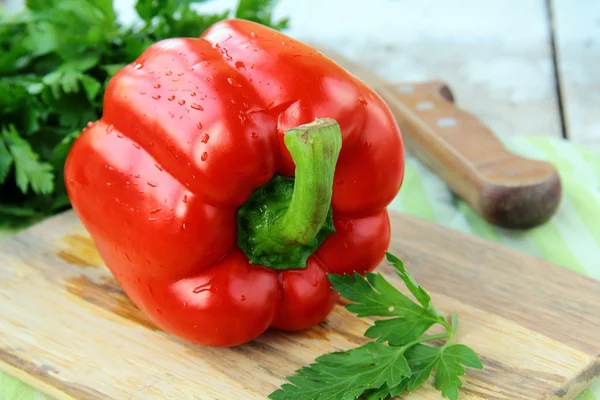 Stor rød klokke paprika peberfrugter på et skærebræt - Stock-foto