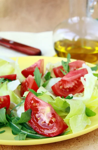 Fresh salad with tomato and arugula, olive oil in the background — Stock Photo, Image