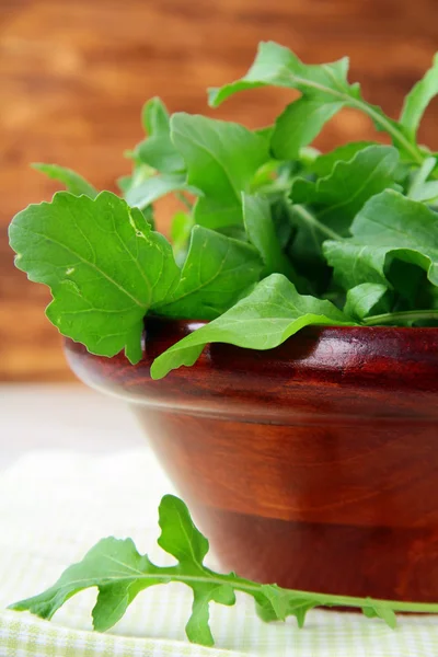 Wooden cup with a green fresh arugula on the table — Stock Photo, Image