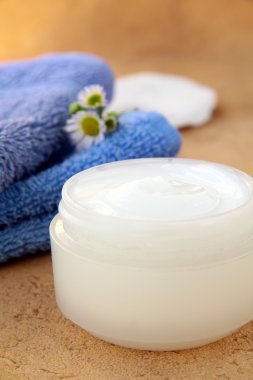 Cream for face and body in bank and towel in the background clipart