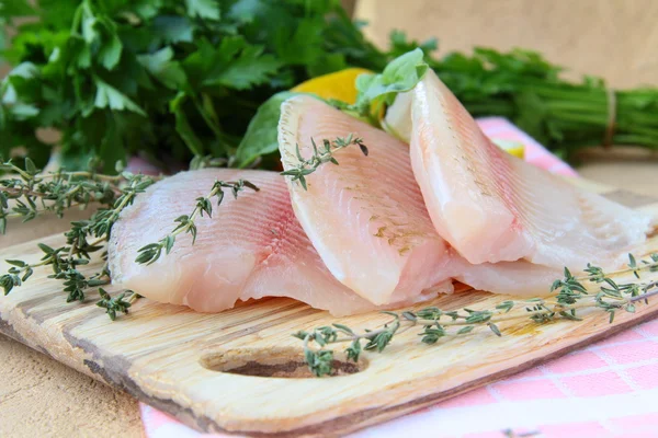Filete de pescado fresco crudo con hierbas y especias en una placa de cocina — Foto de Stock