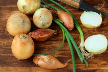 Several types of onions - green and shallots on a wooden background