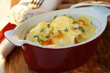 Potato gratin dauphinoise in the pan on rustic background clipart