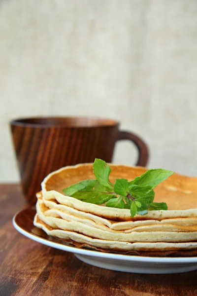 Traditionelle amerikanische Pfannkuchen auf einem Teller mit einem Zweig Minze auf einem braunen Rücken — Stockfoto