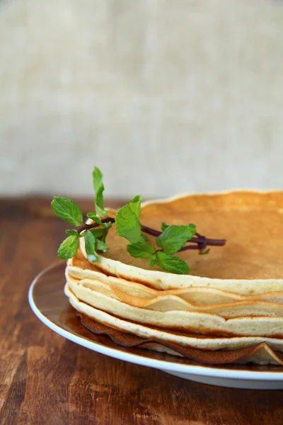 Traditionella amerikanska pannkakor på en tallrik med en gren mynta på en brun rygg — Stockfoto