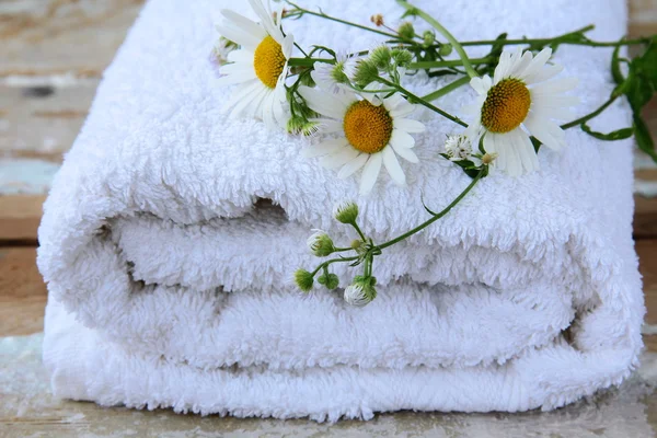 Witte handdoek met margrieten op een houten tafel — Stockfoto