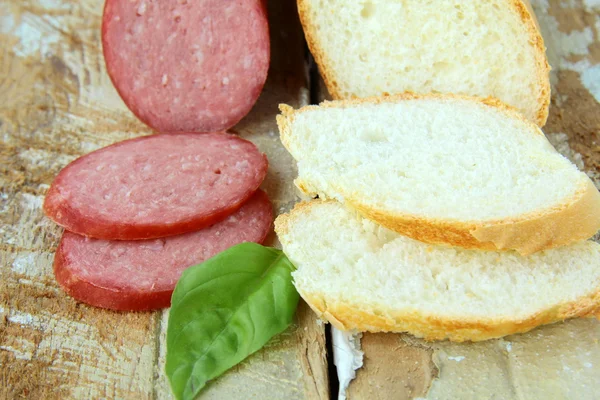 stock image White baguette and salami on a wooden table