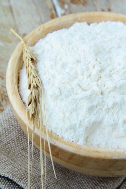 White flour in a wooden bowl with the wheat spikelet clipart