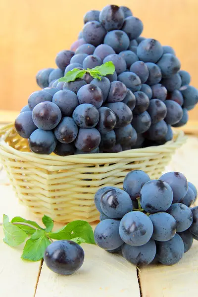 Zwarte borstel zoete druiven in een mand op houten tafel — Stockfoto
