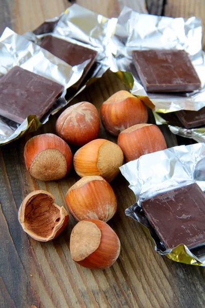 Cokelat lezat dengan hazelnut di atas meja kayu — Stok Foto