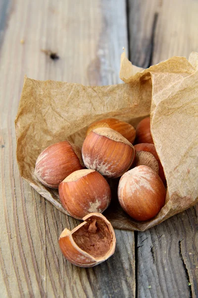 Орешки в бумаге на деревянном столе — стоковое фото