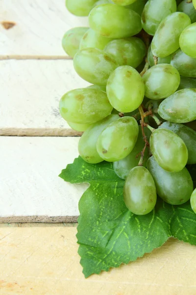 Branch of green grapes on a wooden background — Stock Photo, Image