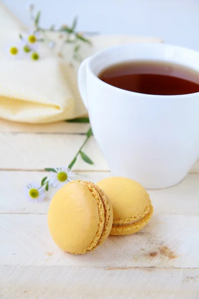 Sobremesa francesa macaroons amarelos e uma xícara de chá no fundo — Fotografia de Stock