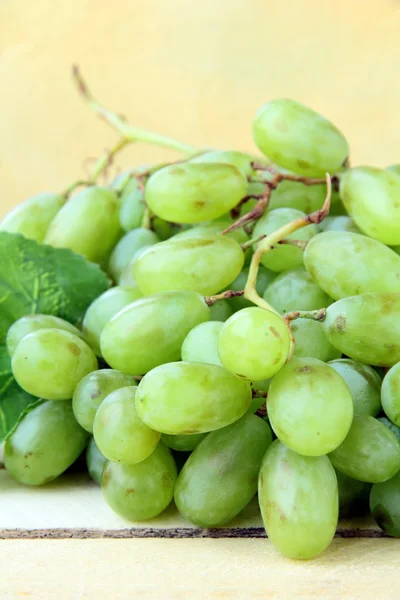 Ramo de uvas verdes sobre um fundo de madeira — Fotografia de Stock