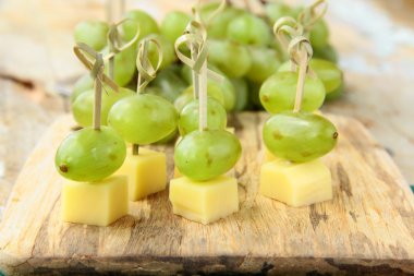 Appetizer canape cheese with white grapes on bamboo skewers clipart