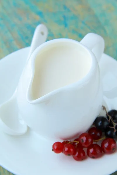 Bílý džbánek s mlékem a ovocem na dřevěné pozadí — Stock fotografie
