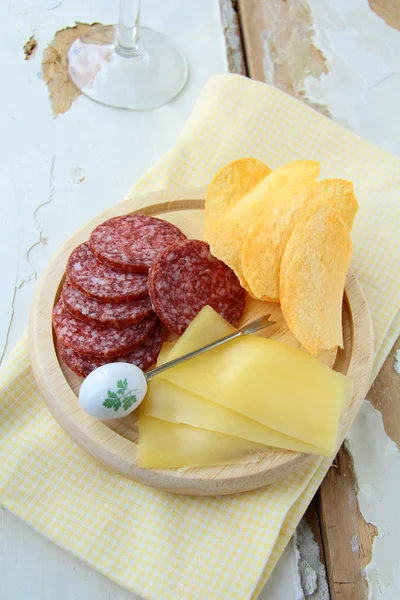 Salami, queso y papas fritas, merienda en una tabla de madera —  Fotos de Stock