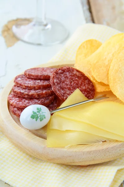 Salame, queijo e batata frita, lanche em uma tábua de madeira — Fotografia de Stock