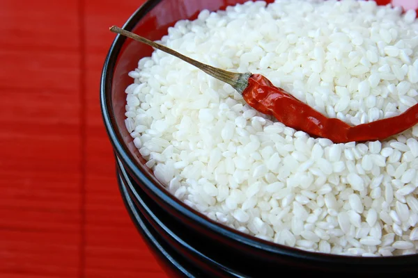 Белый рис в черной миске с перцем чили на красном фоне — стоковое фото