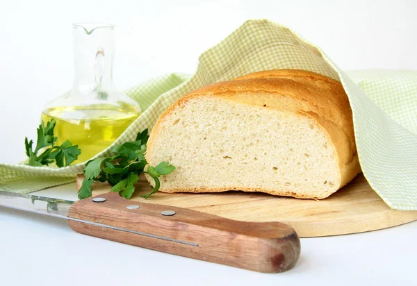 Fresh white loaf of bread with a knife and olive oil — Stock Photo, Image