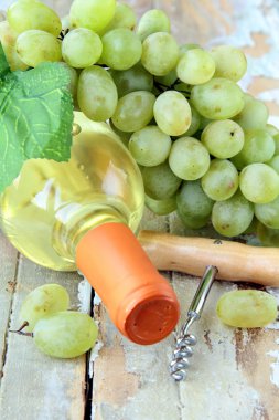 Bottle of white wine, grapes, and a corkscrew on a natural background clipart