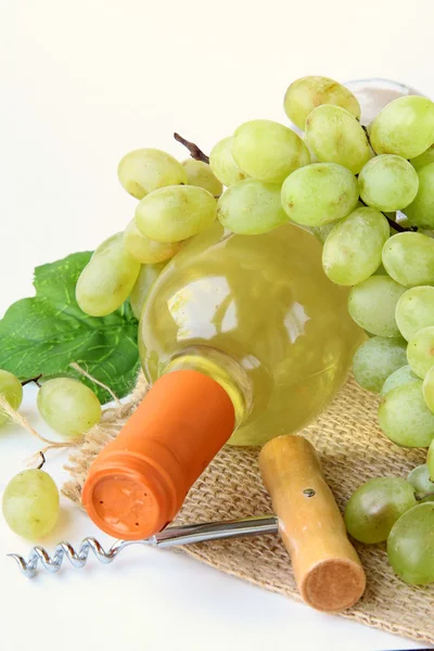 Bottle of white wine, grapes, and a corkscrew on a natural background — Stock Photo, Image