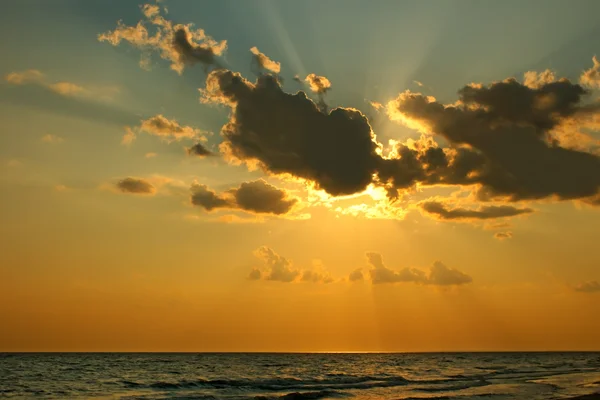 Sun behind a cloud over sea