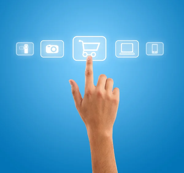 Hand pressing shopping cart symbol from media icons on blue back — Stock Photo, Image