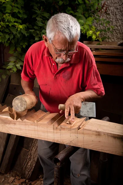 Alter Holzschnitzer arbeitet mit Holzhammer — Stockfoto