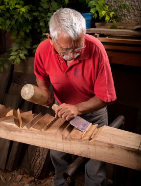 Old woodcarver working with mallet clipart