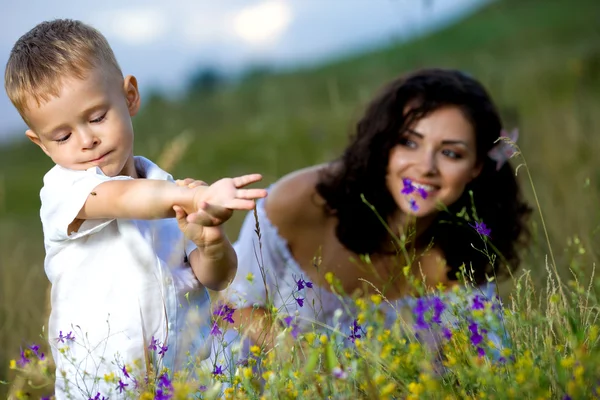 Mother and son sitting in flowers — Stock Photo, Image