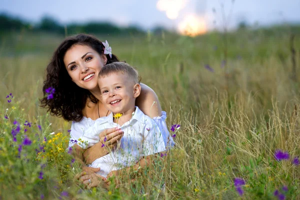Mor och son sitter i blommor — Stockfoto