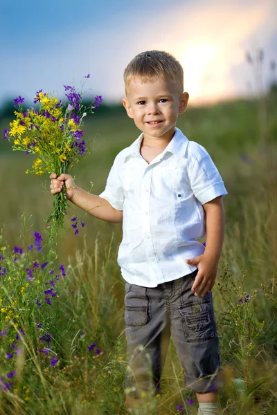 Liten pojke med blommor i händerna — Stockfoto