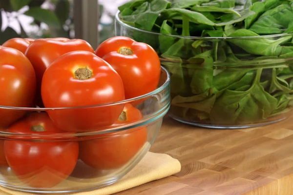 Frische Tomaten und Spinatschalen — Stockfoto