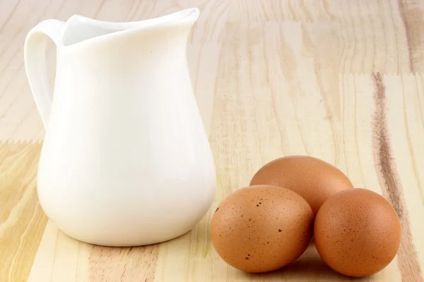Mjölkflaska och brun råa ägg — Stockfoto