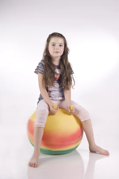 Menina em uma bola de borracha colorida — Fotografia de Stock